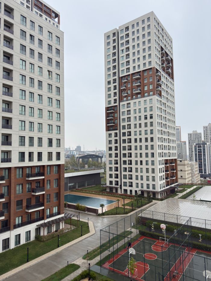 Modern high-rise buildings with basketball courts and pool in urban residential area.