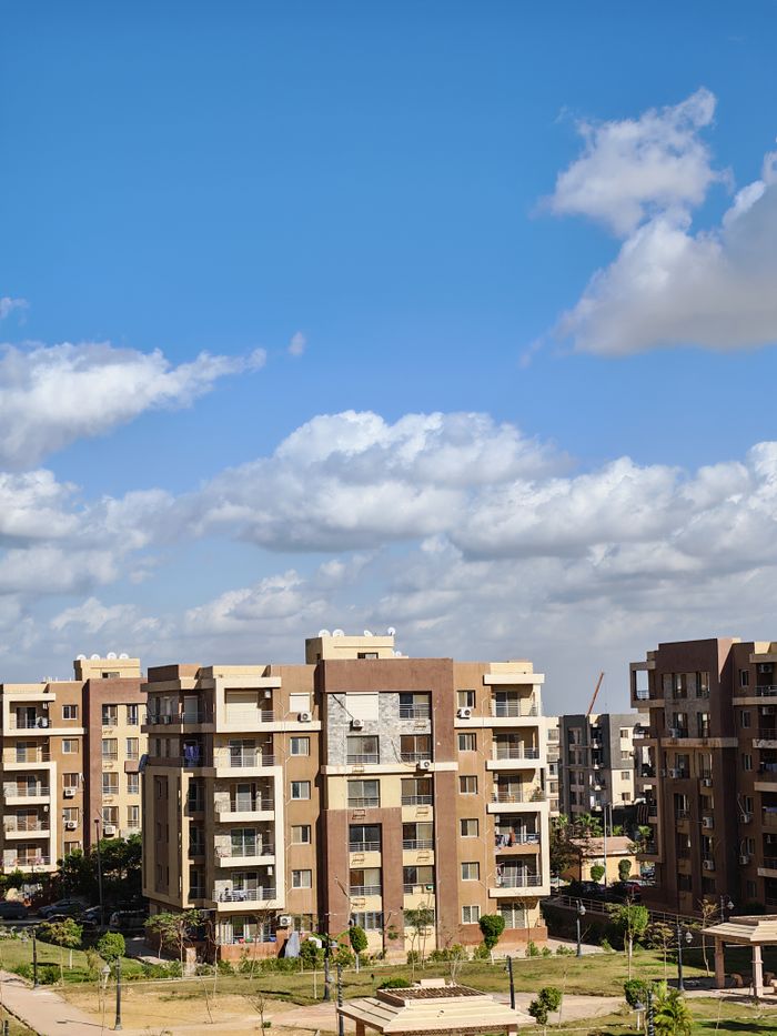 Contemporary apartment complex with bright blue sky and clouds.