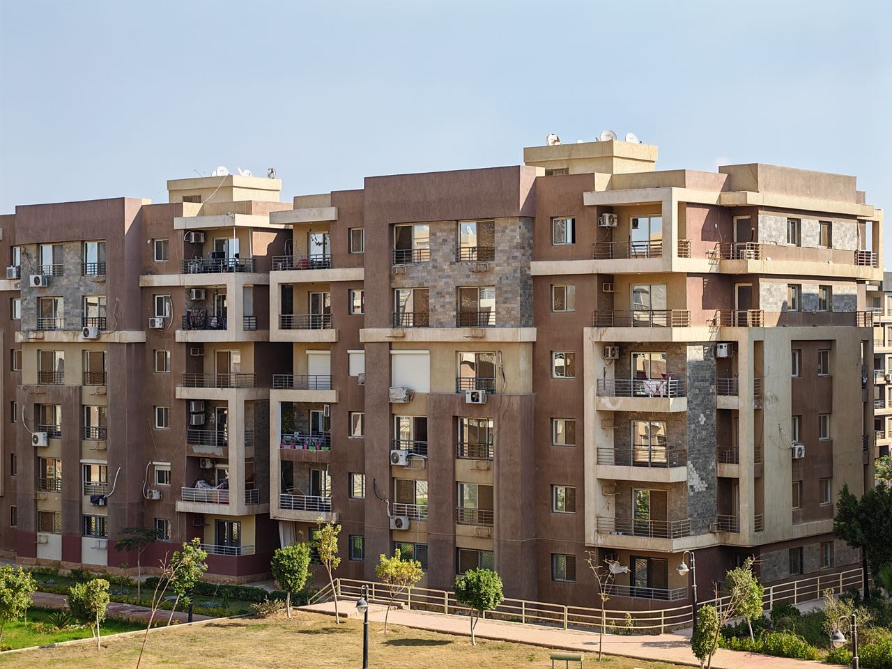 Contemporary multi-story apartment building with balconies in a sunny urban setting.